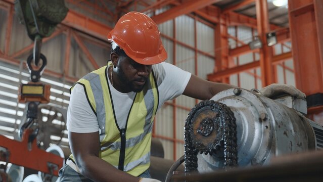 Engineer or operator wearing a safety suit maintaining machine in the industrial factory, service technicain worker operating tighten the nut repair machinery at metal sheet factory