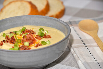 Bowl of potato soup topped with cheddar cheese, bacon and green onions