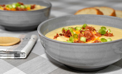 Bowl of potato soup topped with cheddar cheese, bacon and green onions