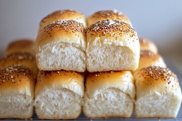 Freshly baked golden bread rolls stacked on a cooling rack with a soft background