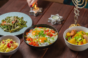 A Jewish woman lights Shabbat candles at a festive table