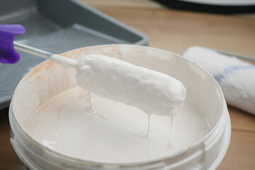 Painting with a roller dipped in white paint on a tray