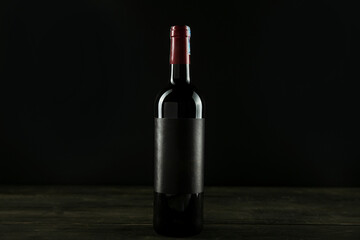 Bottle of red wine. Dark glass bottle with blank label mock up on black backdround