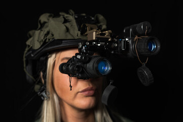 Portrait of a blonde woman in a modern tactical helmet with advanced binocular night vision goggles against a dark background.