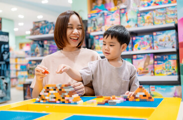 Fototapeta premium Mother and son playing with building blocks in toy store