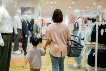 Mother and son holding hands walking in clothing store