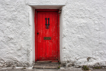 A rustic red door with a number 11 sign, set into a rough white plaster wall.