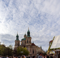 
A baroque church with several green domes and turrets, located in a bustling town square.