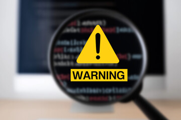 Magnifying Glass Focused on Warning Sign – Cybersecurity Alert and Code Threat Concept