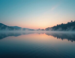 Obraz premium A tranquil dawn scene reveals mist hanging over a serene lake reflecting soft sunrise colors.