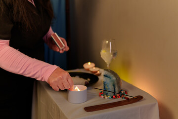 Therapist lighting a candle during a spiritual ritual with palo santo, crystals, and other elements
