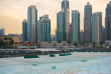 Modern skyscrapers of Downtown Dubai behind the fountain area during sunset. The Dubai Fountain is...