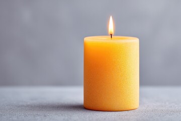 subdued table set with solitary lit candle against simple gray background