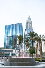 Fototapeta premium Decorative city fountain surrounded by palm trees and high-rise buildings in modern Dubai
