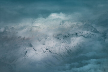 breathtaking aerial view of the snow covered peaks of the Himalayas, showcasing dramatic cliffs, deep valleys and serene glaciers under blanket of clouds in the world highest mountain range