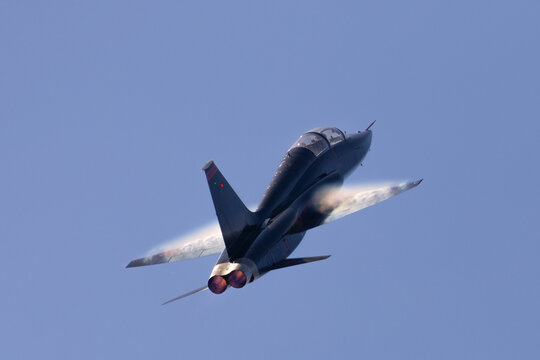 tail view of aT-38 talon (US military trainer) in a high-G maneuver, with condensation trails at the wings, and afterburners on.