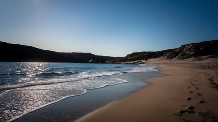 Secluded Moonlit Beach with Waves, Footprints, and Rocky Coastline Serenity