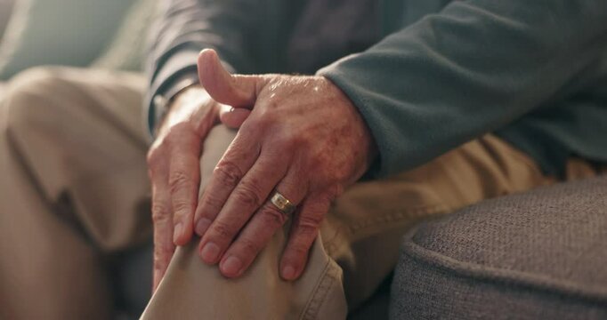 Hands, knee pain and old person with injury, arthritis or osteoporosis with muscle or joint ache in home. Torn ligament, discomfort and bone fracture, man on sofa with leg pressure or tension massage