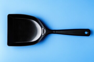 Black cooking scoop on a bright blue background.  The scoop has a smooth, matte finish and a handle