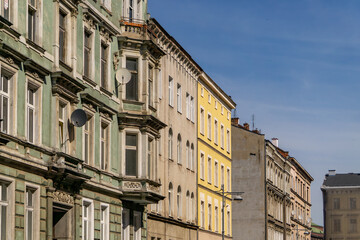 row of historic tenement houses in the Classicist and Art Nouveau styles, typical of Central European architecture. The buildings are decorated with architectural details and have a variety of facade 