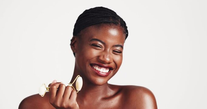 Derma roller, black woman and gua sha on face for beauty, acne or blood circulation in studio on white background. Cosmetic, quarts stone and product for lymphatic drainage, wellness and skincare