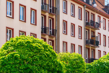 Colorful tenement houses with balconies against the background of lush green bushes on a sunny day. urban architecture