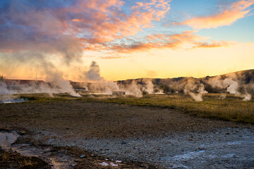 Twilight skyline with Geysers hot spring in Iceland. Winter cold colors, sun lighting through the steam