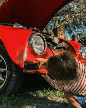 Little Helper: Child Inspecting a Vintage Automobile
