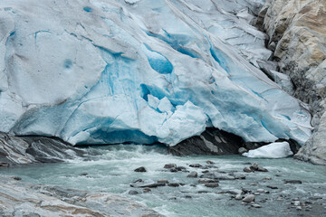 Close up of beautiful blue ice in a Norwegian glacier with gushing meltwater