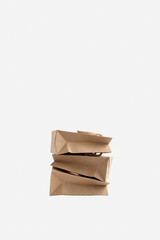 Shopping bags made of recycled paper on a white background. The craft bags are stacked on top of each other. The concept of packaging, shipping, shopping