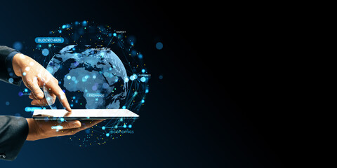 Businessperson using digital tablet with holographic globe and blockchain network on dark background for innovation and technology concept.