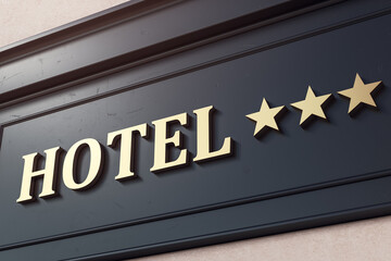 Obraz premium Hotel signage on dark building facade with three gold stars indicating ranking, modern exterior design with clear background lighting outdoors. 3D Rendering