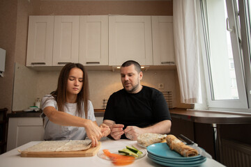 Domestic kitchen scene with two people assembling lunch or dinner.