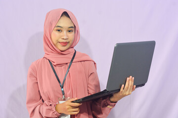 Portrait of a smart-faced Muslim female student wearing glasses, holding her laptop