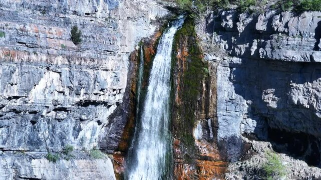 Aerial upper Bridal Veil Falls Provo Utah close descend 1. 607 foot tall double cataract waterfall in Provo Canyon. Rugged rocky ledges and cliffs over pine forests. Deep canyon valley. Summer.