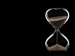Glass hourglass on black background and copy space.