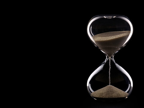 Glass hourglass on black background and copy space.
