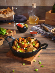 Vertical image a fried potatoes with onions and dill in a black cast iron frying pan.