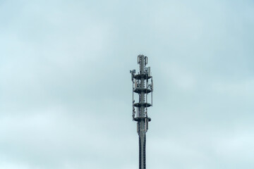 Obraz premium Telecommunication tower stands tall against a cloudy sky in a rural landscape during the day