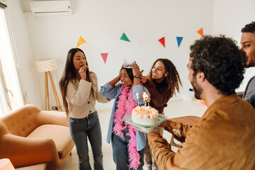 A group of multiethnic adult friends with party whistles celebrating their birthday with a festive...