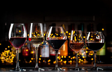 Wines in glasses set. Red, white, rose wine on dark background with bottles. Bar, shop, tasting or degustation