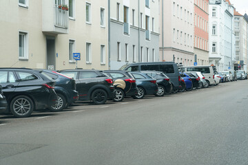 Urban street view showcasing parked vehicles along a residential block on a cloudy day