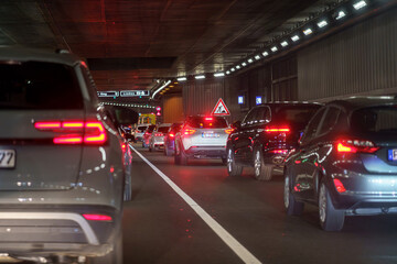 Traffic congestion in an urban tunnel during late evening rush hour with illuminated road signs and vehicles lined up