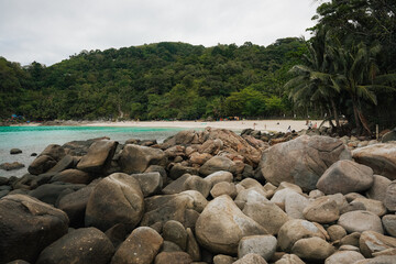 High-resolution tropical coast wallpapers featuring Phuket, Thailand: vibrant turquoise water lapping golden sand, a traditional long-tail boat near a palm-fringed cove, and a solitary sailboat drifti
