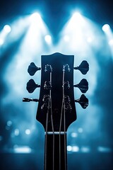 Bass guitar headstock on a stage, illuminated by spotlights.  The headstock is dark, and the background is a blurred, lit stage