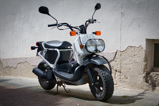 Ein weisser PGM-F1 Zoomer von Honda auf einem Gehweg geparkt