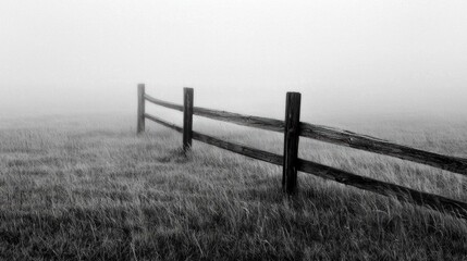 Black and white photograph of a wooden fence in the middle of a field. the fence is made of wooden planks and posts, and is supported by two wooden posts on either side.