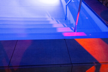 A modern swimming pool illuminated with purple lights, offering a tranquil nighttime setting.