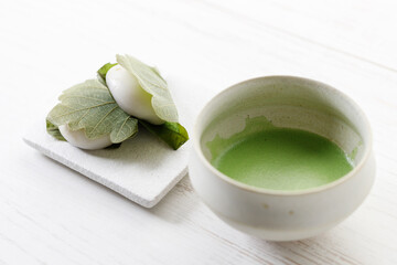 Kashiwa mochi and Cup of fresh matcha tea. Japanese sweet from mochi or rice cake and sweet red bean paste filling surrounded with Kashiwa or Oak leaf .