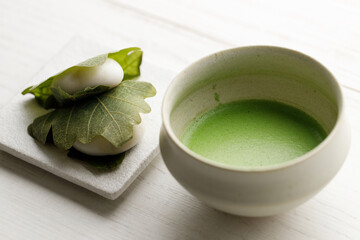 Kashiwa mochi and Cup of fresh matcha tea. Japanese sweet from mochi or rice cake and sweet red bean paste filling surrounded with Kashiwa or Oak leaf .